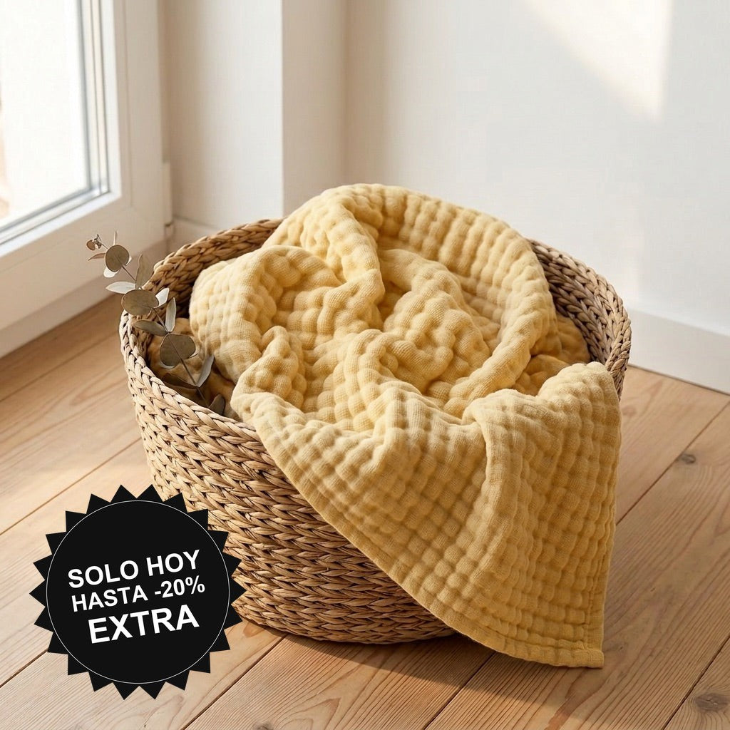Manta de muselina NubeSuave color Amarillo crema — en una cesta junto a la ventana